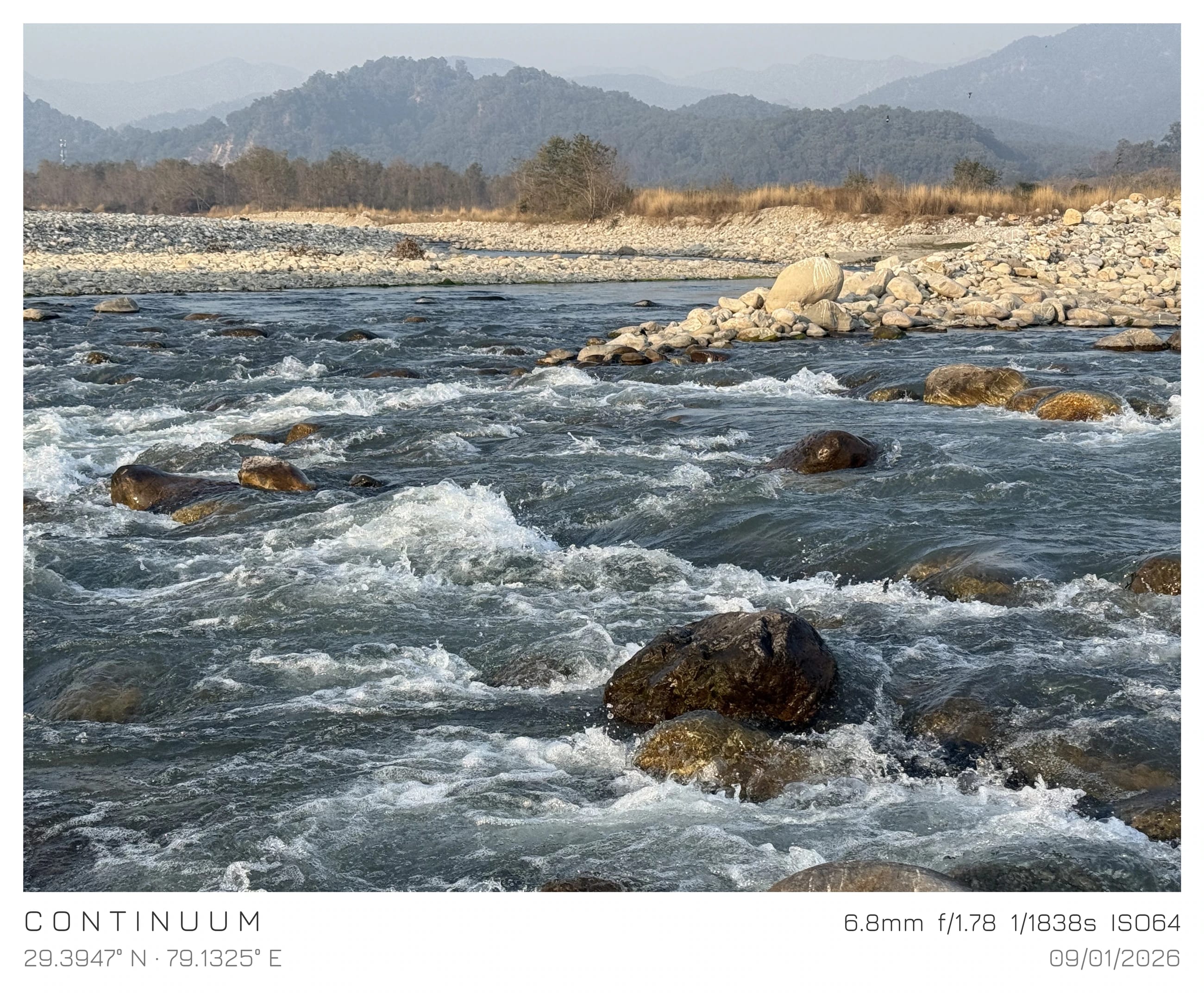 A river flowing over stones with mountains beyond